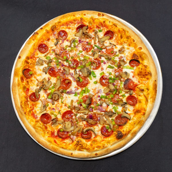 A whole pepperoni, mushroom, green pepper, and red onion pizza on a metal pan.