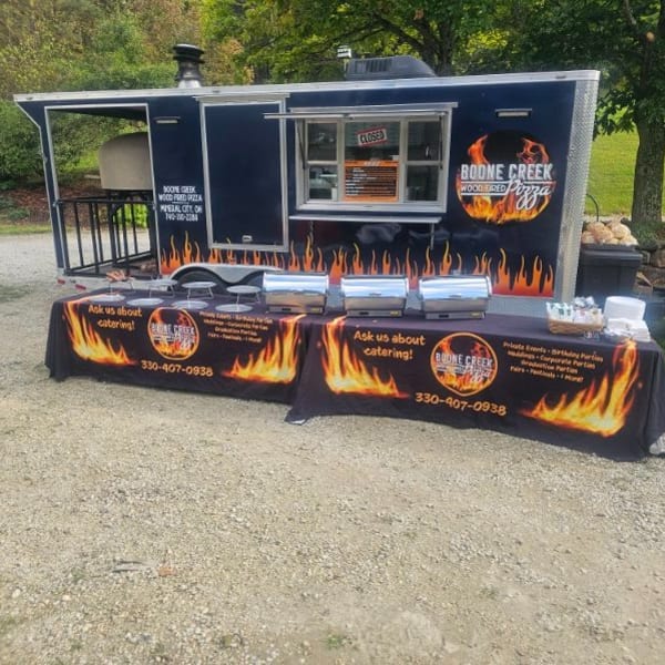 Boone Creek Wood Fired Pizza food truck with a catering table set up outside.