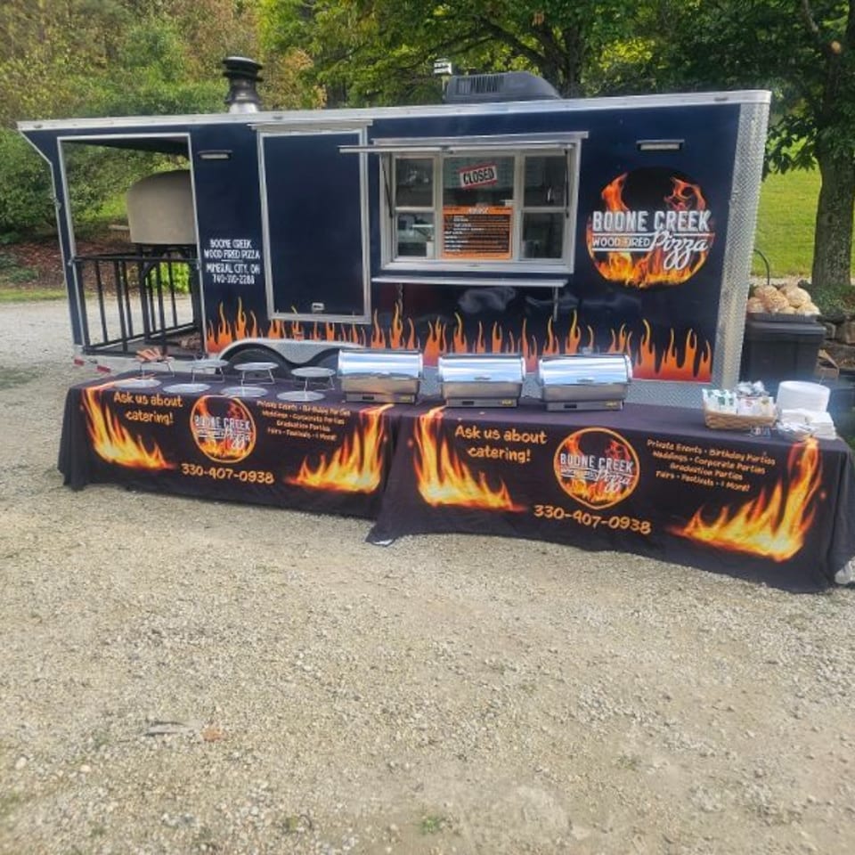 Boone Creek Wood Fired Pizza food truck with a catering table set up outside.