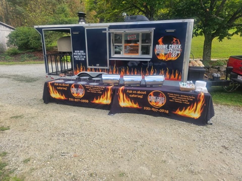 Boone Creek Wood Fired Pizza food truck with a catering table set up outside.