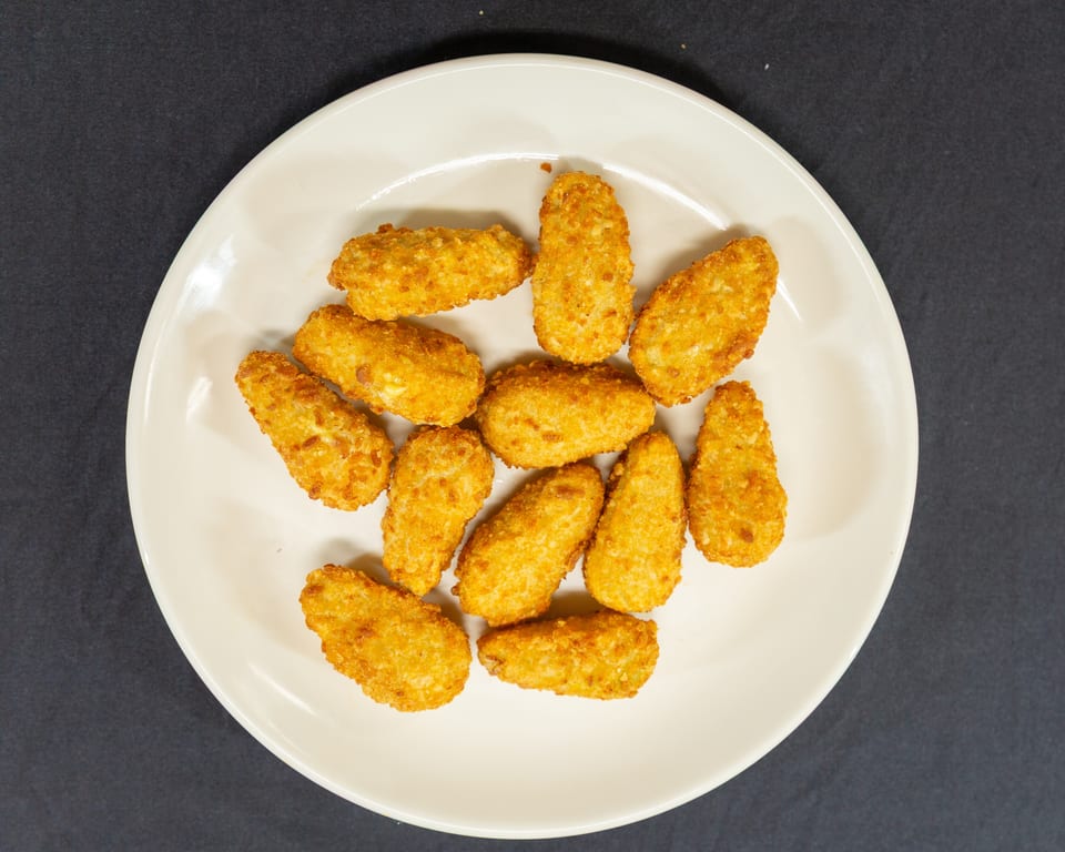 A white plate filled with golden-brown, breaded fried cheese curds on a dark background.