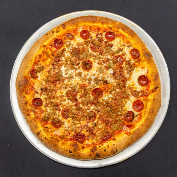 A whole pepperoni and sausage pizza on a metal tray, viewed from directly above.