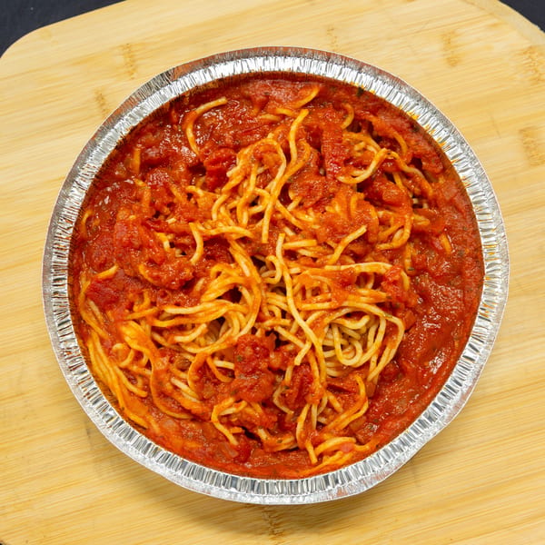 Spaghetti with red sauce in a round foil container on a wooden board.
