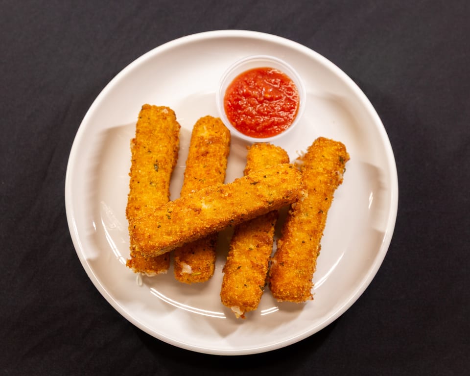 Golden-brown mozzarella sticks with a side of red marinara sauce on a white plate.