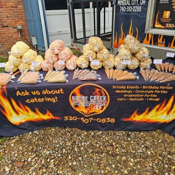 Boone Creek Wood Fired Pizza catering table with various popcorn bags and cones.